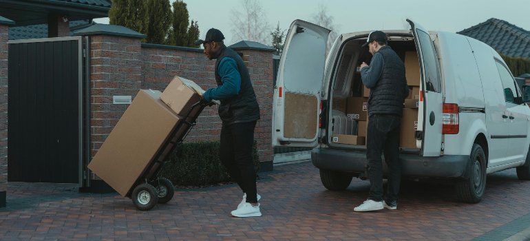 Cincinnati Apartment vs House Moves: What’s the Difference? 1 Professional movers unloading boxes from a van into a driveway, showing easier access during house relocations in apartment vs house moves.