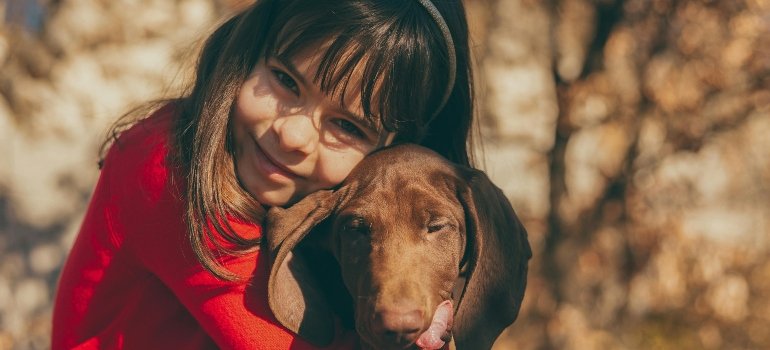 Moving With Kids To Loveland Ohio: What to Expect 3 A Young Girl in Red Long Sleeves Embracing Her Dog