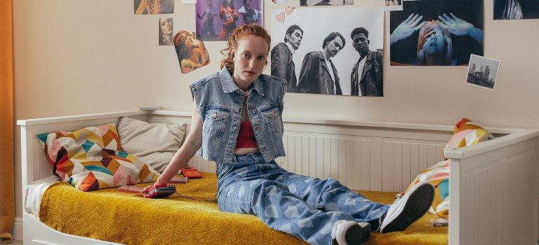 Tips for Moving to a New City Alone 3 Person settling in after moving to a new city alone, with bed unpacked and posters on the wall.