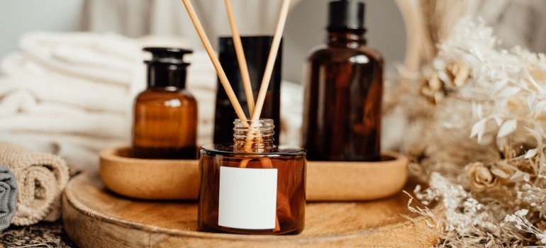 How To Clean An Apartment Before Moving In 4 A wooden tray with amber glass bottles, a reed diffuser, and soft towels, surrounded by dried flowers