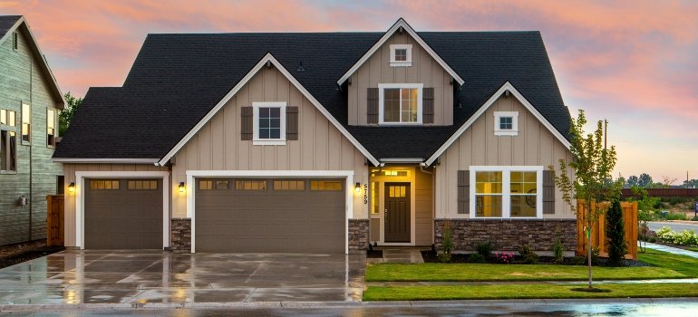 Actionable relocation guide to Hamilton Ohio 2 Craftsman-style suburban house with three-car garage at sunset on a rain-wet driveway.