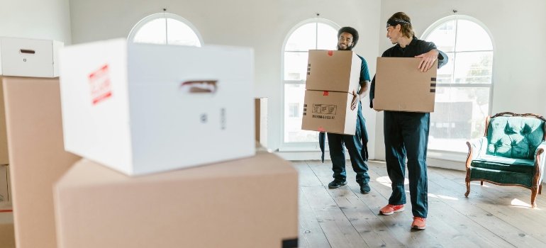 A Local’s Guide to the Best Suburbs of Cincinnati Ohio 5 Two professional movers carrying boxes inside a bright home, representing moving services available in the best suburbs of Cincinnati Ohio.