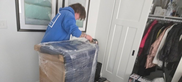 How to prepare for a winter relocation in Ohio? 1 Mover wrapping furniture inside home during winter relocation in Ohio