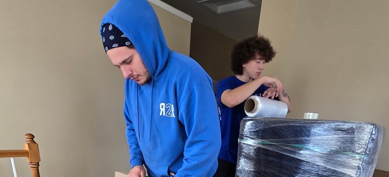 How to efficiently pack for your move 4 Professional movers packing boxes and wrapping furniture