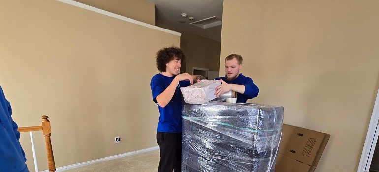 Tackling hoarding before a move 3 Professional movers wrapping protected furniture on moving day