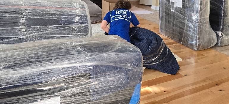 Tips for moving into a smaller apartment 2 Professional movers wrapping furniture when moving into a smaller apartment