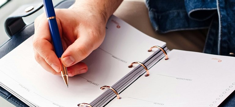 Maximizing daylight during your February move: Tips for a smooth transition 2 a person writing moving schedule in open ring planner