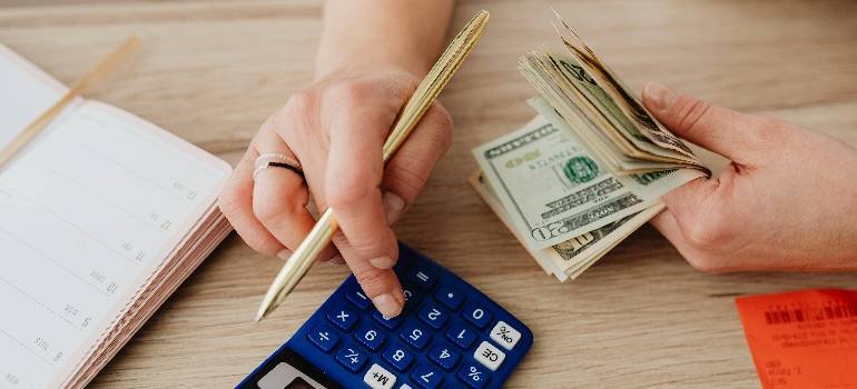 The ultimate guide for a spring move to Harrison OH 5 Person counting moving budget cash with blue calculator